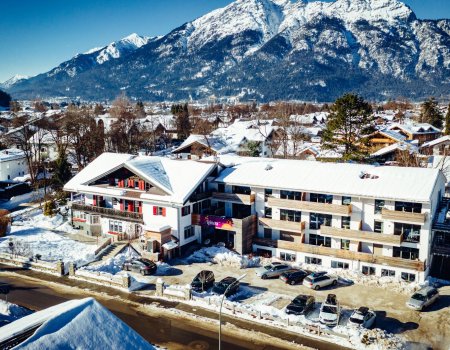 Vogelperspektive auf schneebedeckte Häuser und Autos vor Bergen unter klarem Himmel