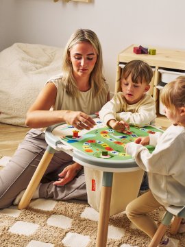 Mutter spielt mit Kindern auf Spieltisch