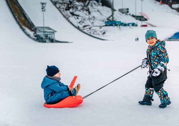 Jung zieht Junge auf Rodel